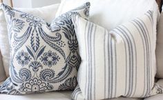 two blue and white pillows sitting on top of a couch