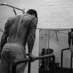 a man standing in front of a mirror with his back turned to the camera while holding onto a bar