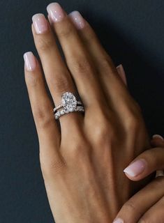 a woman's hand with two engagement rings on it