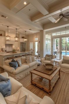 a living room filled with furniture next to a kitchen and dining room table in front of a pool