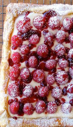 a pastry with powdered sugar and berries on top is sitting on a cooling rack