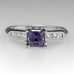 This gorgeous blue to purple color change sapphire engagement ring features a 1.16 carat no heat sapphire with Montana, USA origin that we sourced and set in a vintage platinum diamond mounting. The shoulders of the ring are each accented with three (3), channel set, round single cut diamonds, bordered with milgrain edging. The ring measures 6.2mm at the top, rises 6.3mm above the finger, tapering to 1.5mm wide and 1.3mm thick at the base of the shank. The ring is currently a size 5.75 and we offer complimentary resizing to fit. Classic Purple Sapphire Promise Ring, Purple Sapphire Ring With Brilliant Cut For Anniversary, Classic Purple Sapphire Ring For Wedding, Classic Purple Sapphire Wedding Ring, Classic Purple Sapphire Ring With Prong Setting, Classic Sapphire Rings In Purple, Silver Platinum Sapphire Ring With Channel Set, Elegant Sapphire Tanzanite Ring In Silver Color, Luxury Purple Brilliant Cut Sapphire Ring