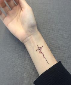 a woman's wrist with a small cross tattoo on the left side of her arm