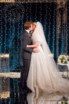 a bride and groom kissing in front of a blue backdrop