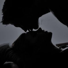 two people are kissing in the dark with their heads close to each other's faces