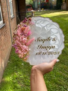 a person holding up a glass plate with flowers on it in front of a brick building