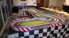 a toy race track set up in the middle of a room with tables and chairs