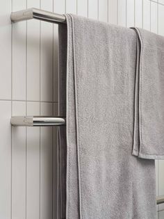 a towel rack with two towels hanging from it's sides in front of a white tiled wall