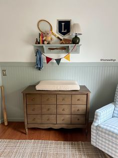 a baby's room with a crib, chair and wall hanging on the wall