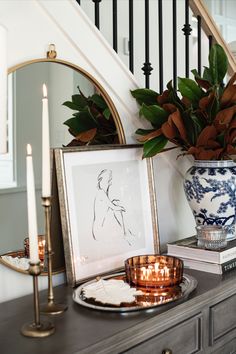 a vase with flowers and candles on top of a dresser next to a framed photograph