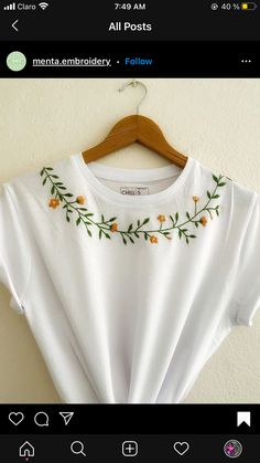 a white t - shirt with orange flowers on the front and green leaves on the back