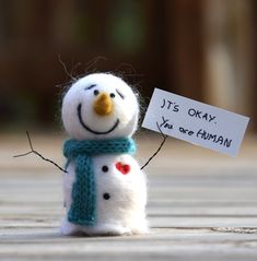 a small snowman with a sign that says it's okay you are human