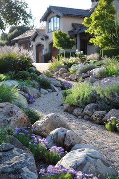 a house with lots of rocks and flowers in the front yard