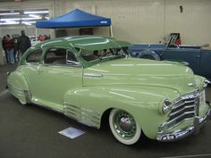 an old green car parked in a garage