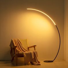 a chair with a blanket on it next to a light that is turned on by a lamp