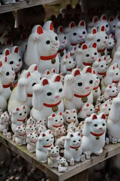 there are many white cat figurines on display