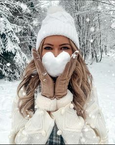 a woman wearing gloves and mittens covers her face with snow in the wintertime