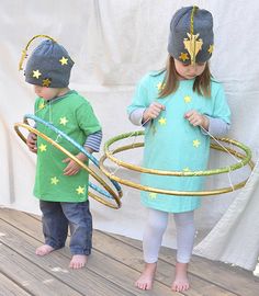 two young children standing on a wooden deck holding hoopglings and wearing knitted hats