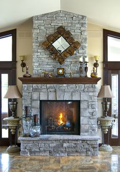 a living room with a fire place in the center and two lamps on either side