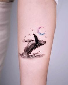 a tattoo on the arm of a woman with a whale jumping out of the water