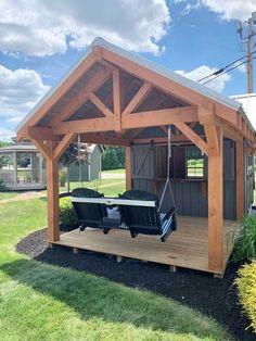 a wooden shed with two chairs on the porch and a swing in the front yard