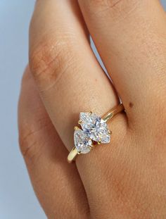 a woman's hand with a diamond ring on top of her finger, showing the center stone