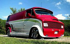 a red and silver bus parked on the side of a road next to some trees