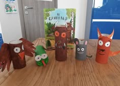 four paper animals are sitting on a table next to a children's bookshelf