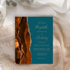 a black and gold wedding card on top of a white blanket