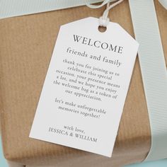 a gift wrapped in brown paper with a white ribbon and tag that reads, welcome friends and family