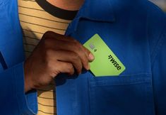 a man in a blue jacket holding a green credit card