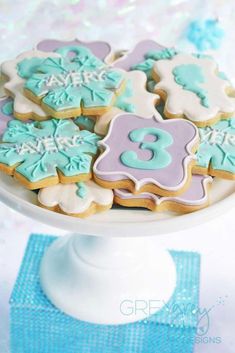 decorated cookies on a white cake stand with blue and purple frosting, number 8