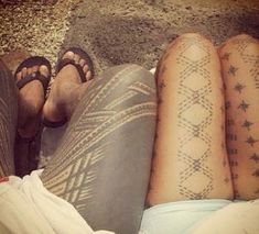 two people with tattoos on their legs laying down