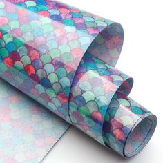 a roll of colored paper on top of a white surface with an image of fish scales