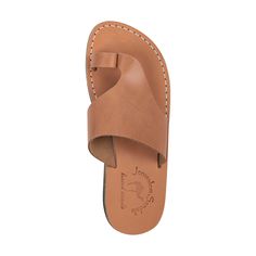 Embrace the sleek contours of the 'Petra' sandal, a silhouette that perfectly balances modern design with classic comfort. Crafted from smooth, full-grain tan leather, this sandal offers a chic and streamlined appearance that complements any outfit. The 'Petra' is a testament to skilled craftsmanship, with a form-fitting design that promotes natural foot movement. Its padded footbed provides a soft, cushioned feel, ideal for day-long wear. A simple, elegant toe loop and a wide upper strap ensure Modern Brown Sandals With Heel Loop, Classic Sandals With Leather Sole And Single Toe Strap, Classic Leather Sandals With Single Toe Strap, Classic Footbed Sandals For Summer Beach, Classic Sandals With Removable Insole For The Beach, Classic Footbed Sandals For Beach In Summer, Classic Beach Sandals With Removable Insole, Classic Toe Loop Flip Flops For Summer, Classic Beach Sandals