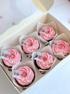 cupcakes with pink frosting in a white box