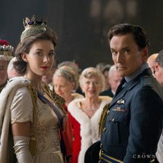 a man in uniform standing next to a woman wearing a tiara and dress clothes