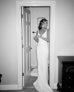 a woman in a long white dress is looking at her reflection in the mirror and smiling