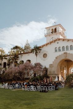 an outdoor ceremony with chairs set up in front of the building and people sitting on the lawn