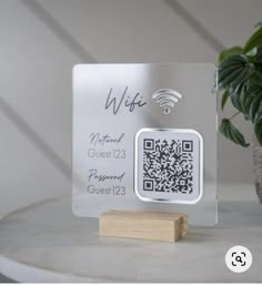 a glass plaque with a qr code on it next to a potted plant