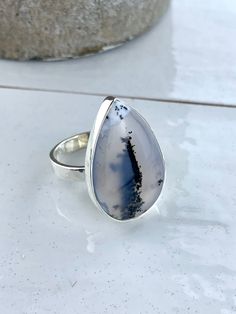 This Genuine Merlinite ring is suspended on a 925 Sterling Silver. Each ring is completely unique. They have been made to show off the very best patterns of the Dendritic Agate  This ring measures 25x18mm  Each piece of Jocale Jewellery comes in a beautiful box making it the ideal gift! Natural Merlinite  , Dendrite Agate , British, English Jewellery, English Jewelry, UK Jewellery, colourful jewellery, colorful Jewelry, pendant, Dendrite pendant, pedants, silver jewellery, unique jewellery, rare gemstone, English Jewellery, unusual jewellery, Unusual Gift, Christmas Gift **Note From Our Gemmologist- Marie Chalmers ** Merlinite is also know as Dendritic Agate. This is because it has plant like inclusions. When you look at it closely you will see it looks as if it has moss like plant growing British Gifts, Colourful Jewellery, English Jewelry, Dendrite Agate, Plant Growing, Jewellery Unique, Aquamarine Pendant, British English, Silver Jewelry Necklace