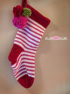 a red and white striped sock hanging on a wall with a pom - pom