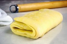 a rolled up pastry sitting on top of a counter next to a rolling pin and towel