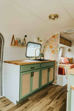 a kitchen with green cabinets and wood flooring in a tiny home on stilts