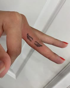 a woman's hand with an angel wing tattoo on her left thumb and finger