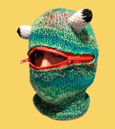 a person wearing a knitted hat with bear ears and eye patch on it's face