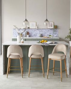 two grey chairs sitting at a kitchen island with marble counter tops and bar stools