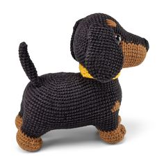 a crocheted black and brown dog with yellow collar sitting on top of a white surface