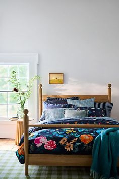 a bed room with a neatly made bed and a plant on the side of the bed