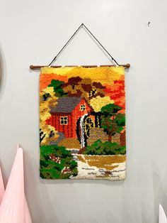 a colorful tapestry hanging on the wall next to a pink vase